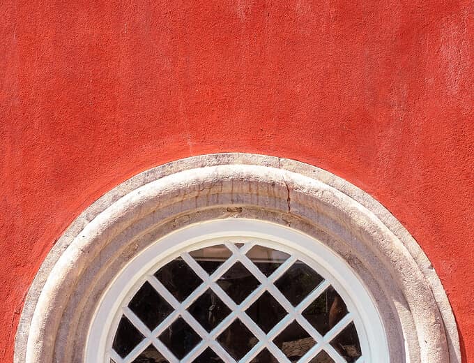 Round window in a red-washed Portuguese wall