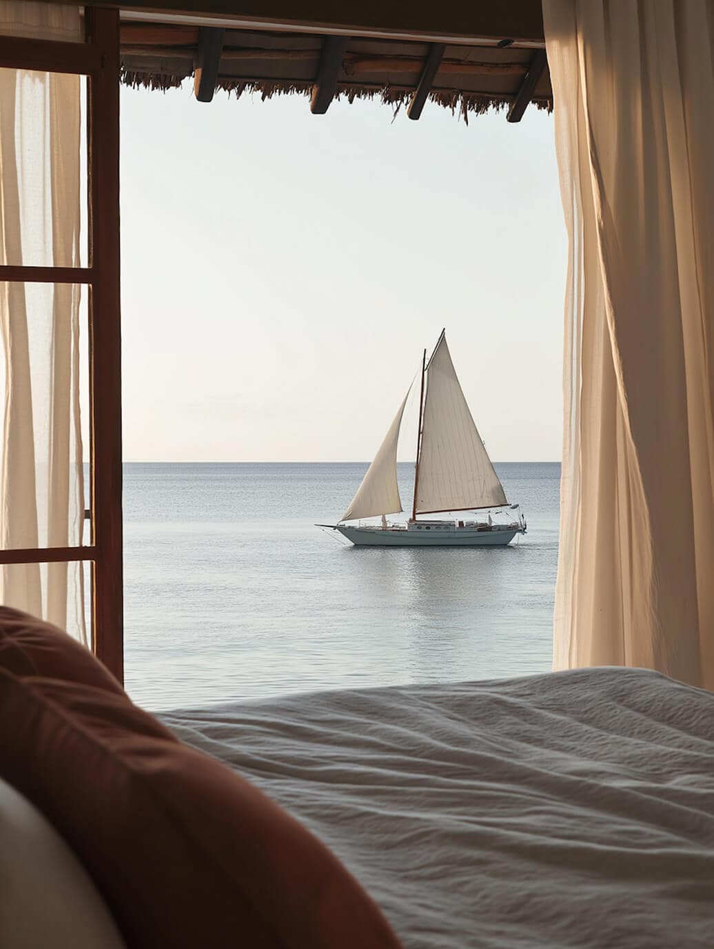 A sailing boat on a calm sea, seen from an open bedroom window